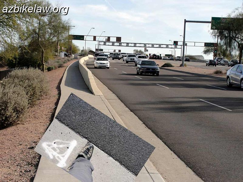ElliotAndI10.jpg - Elliot Road facing west picturing WB traffic coming from I-10 interchange (city of Phoenix).The inset shows the gutter pan is relatively wide (almost exactly 2 feet -- yes my shoes are about 1 foot each!)The lanes are something like 11'. This amount of space if often wrongly perceived by motorists as sharable side-by-side. I think EB is similarly annoying; possibly worse because if i remember correctly there is no RTO lane to enter I-10 eastbound, and this sets up overtaking/right hook problems.Ray/I-10 and Warner/I-10  is set up with nice narrow lanes. Chandler/I-10 is set up with nice wide lanes. Elliot/I-10 is a bastard. Neither fish nor fowl.(speaking only of the Phoenix/West side of I-10).